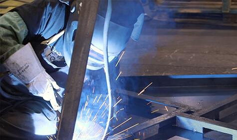 Worker in full protective gear welding.